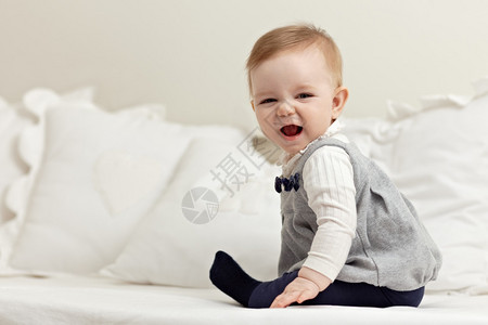 6个月女婴在床上玩耍和对着镜头微笑的肖像水平形状侧视图全长图片