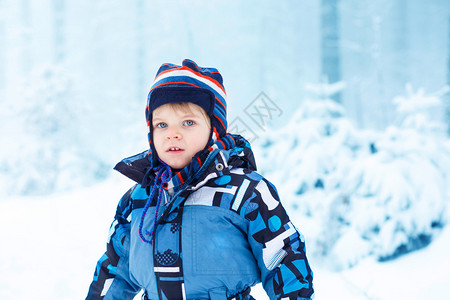 可爱的男孩在美丽的寒冷日与户外雪玩得开心图片