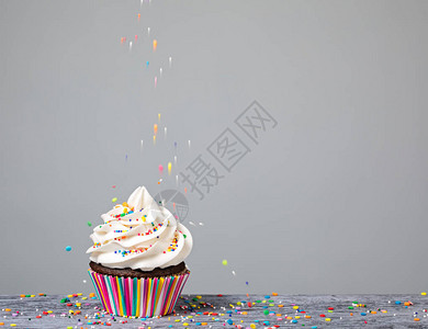 一个纸杯蛋糕上面装饰着五颜六色的花洒图片
