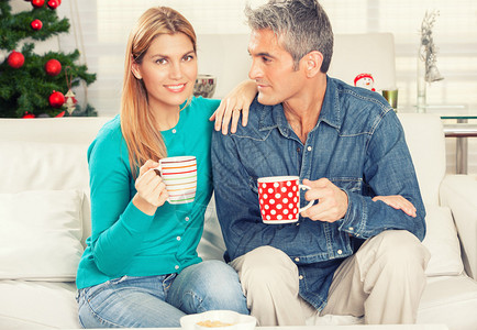 圣诞快乐的情侣在家沙发上喝咖啡图片
