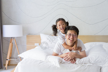 快乐的亚洲家庭父亲和女儿在床上嬉闹图片