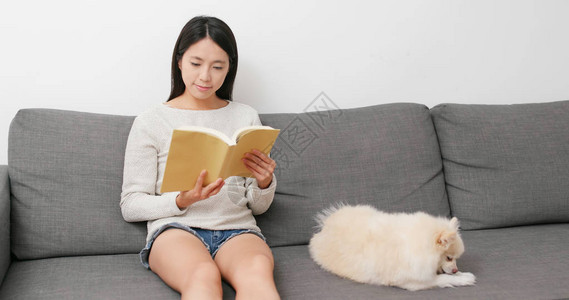 女人在家和她的狗一起看书图片