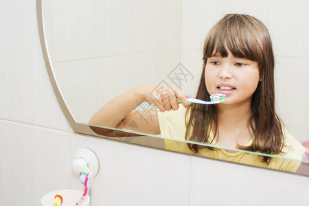 一个女孩在浴室里刷牙望着镜子看图片