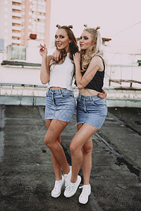 两个时尚女孩最好的朋友穿着牛仔裤裙子图片