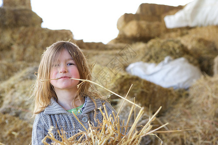 一个可爱的年轻女孩在农场干草场玩耍图片