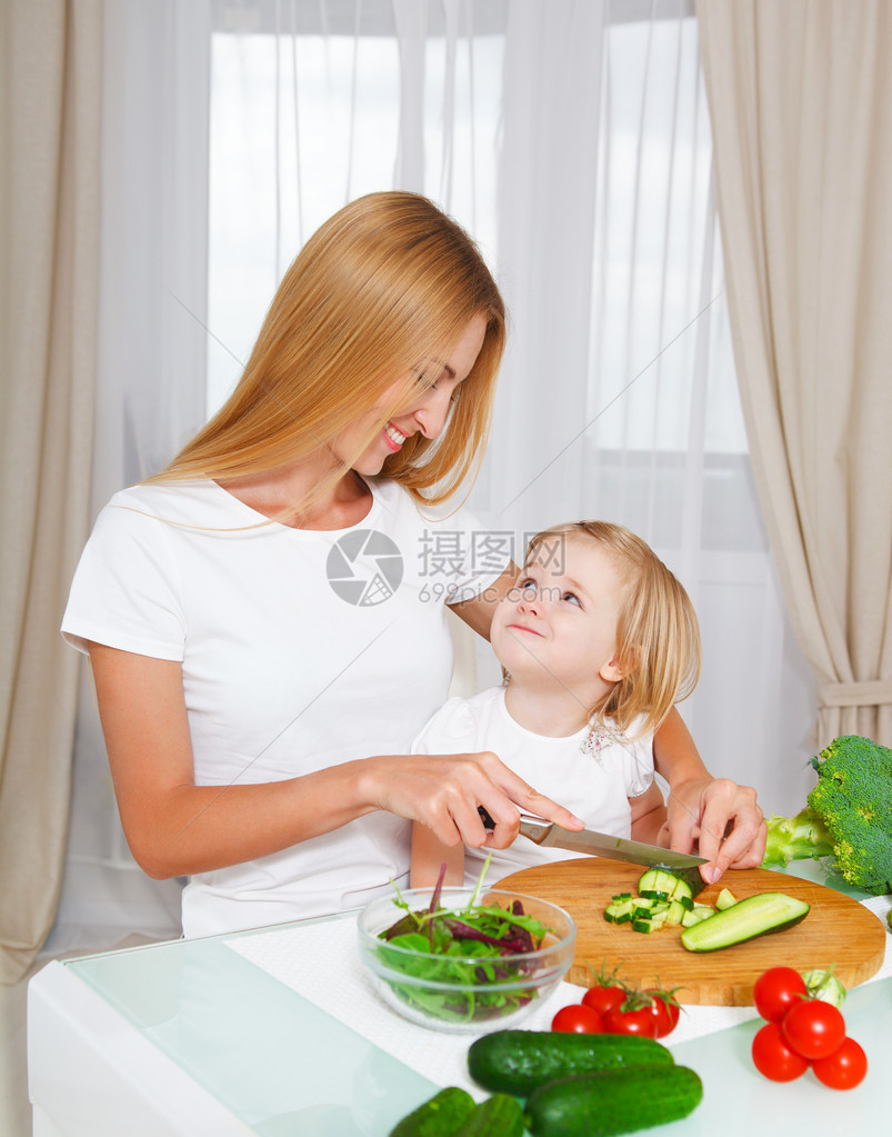 快乐的母亲和女儿在厨房切菜在图片