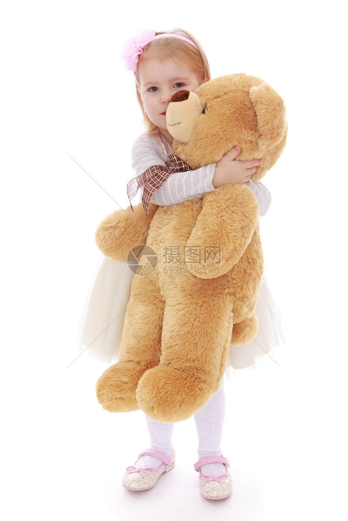 一个小女孩的肖像她拿着一只泰迪熊孤立图片