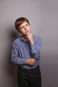 欧洲外表的十几岁男孩棕色头发在灰色背景的脑海深处握着一只图片