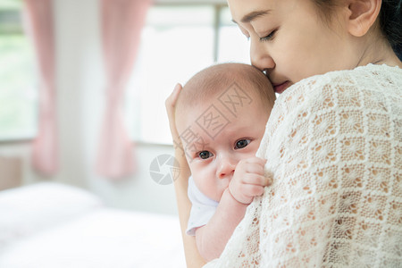 快乐的亚洲母亲在哭后亲吻婴儿男婴的照片在母亲和婴儿图片