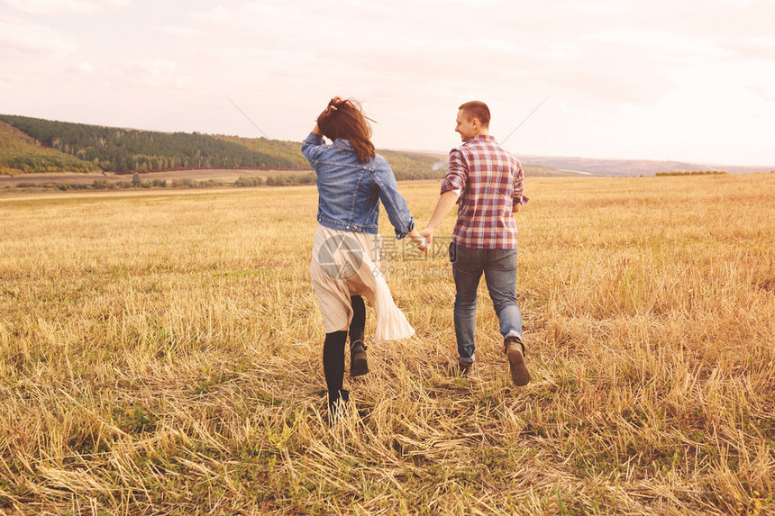 一对幸福的夫妻牵手在草坪上奔跑图片