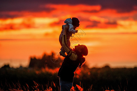 日落背景的快乐母亲与婴儿的肖图片