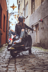 小巷里穿着皮衣的美女坐在摩托上图片