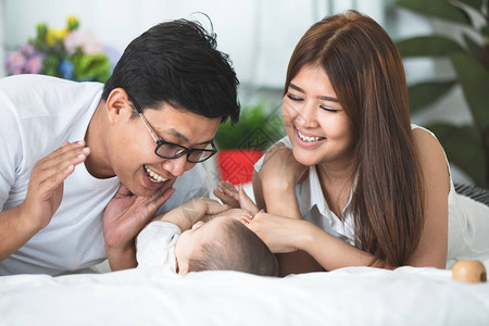 快乐的亚洲家庭父亲母和女儿在床上玩图片
