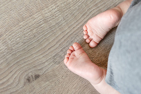 近身可爱的婴儿脚在木质地板背景上有趣的可爱高跟鞋幼图片