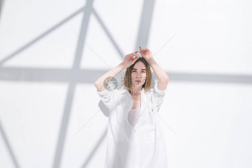 穿着白色衣服的时尚严肃女人站在带有阴影的白色抽象背景上图片