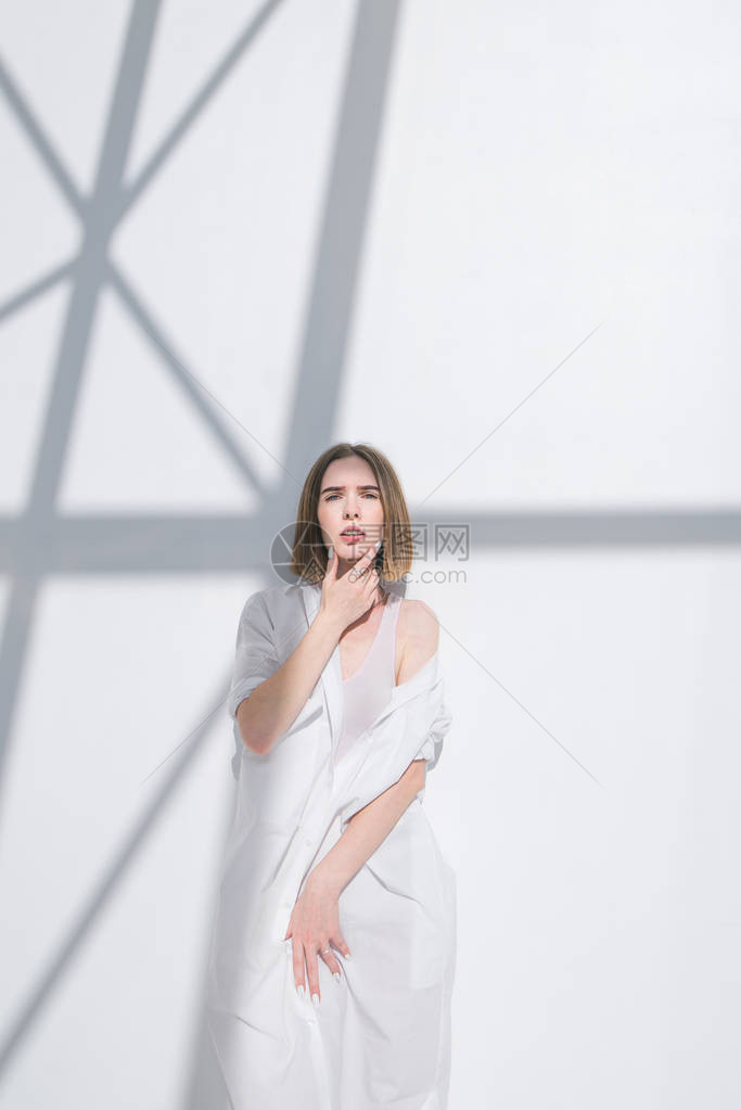 穿着白色衣服在浅色背景上摆姿势的时尚女模特图片