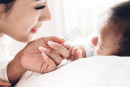 婴儿手在白床上握着母亲的手指图片