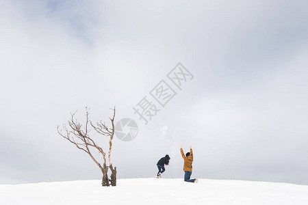 在雪中玩乐和扔雪花的旅游夫妇山图片