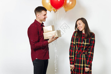 女人和男人拿着带有礼物和红色黄色气球的金色礼盒图片