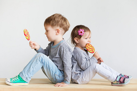 小孩子吃棒糖带着大糖果的快乐孩子一个快乐的小孩男孩和女孩的画像白色背景图片