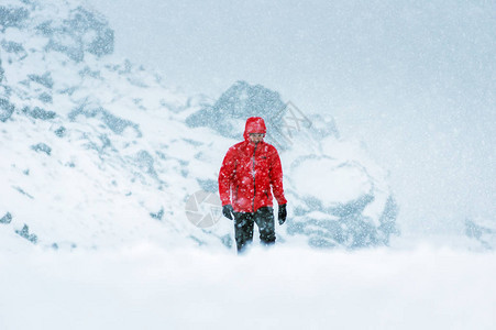 红外套的男人在雪崩时在雪上覆图片
