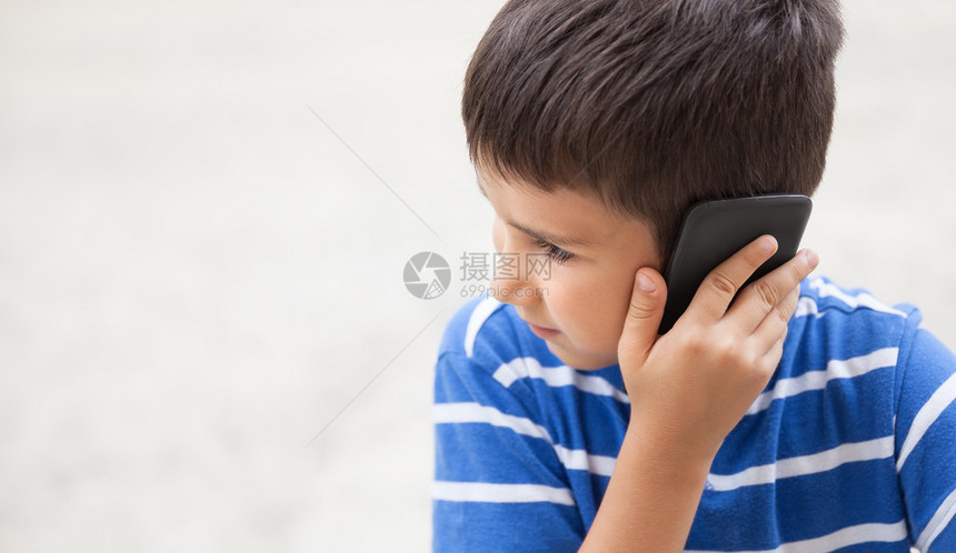 严重小男孩在电话上和父母交谈以轻背景与抄写空间进行通话图片