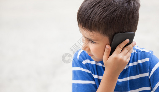 严重小男孩在电话上和父母交谈以轻背景与抄写空间进行通话图片