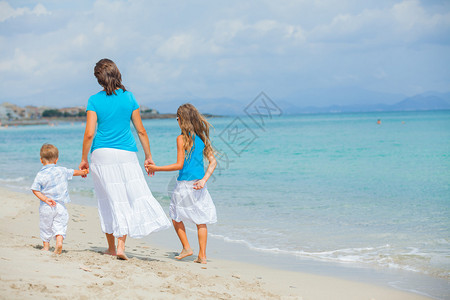 母亲和两个孩子在热带海滩玩图片