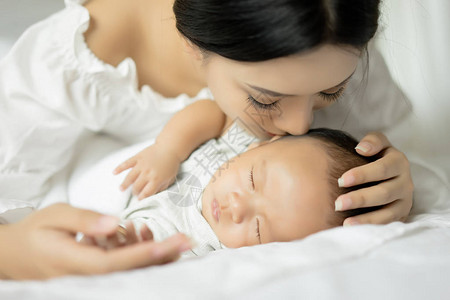 年轻母亲在床上亲吻她新生的婴儿图片