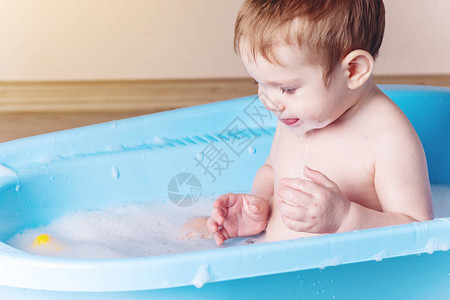 可爱的宝在浴室的蓝色浴缸里洗澡男孩玩图片