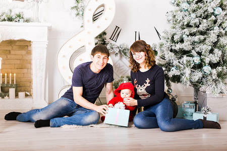 圣诞家庭与婴儿开放礼物快乐的微笑的父母和孩子在家庆图片