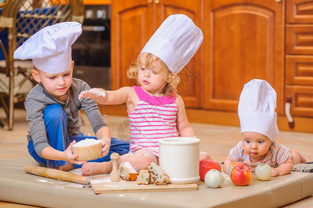两个兄弟姐妹男孩和女孩和一个戴着厨师帽的新生孩子图片