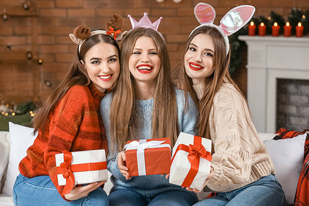 带礼物在家里庆祝圣诞节的美丽年轻女子背景图片