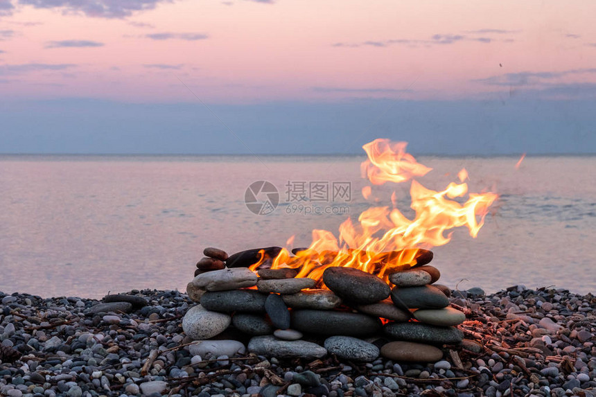 在石头地方海滩和大海背景中燃烧的火图片