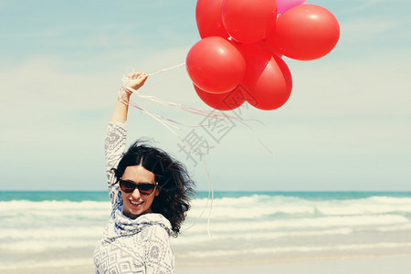 海边拿着红气球的美女图片