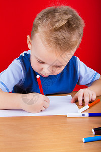 小男孩在桌子上画在红图片
