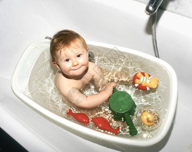 婴儿在他的塑料浴缸里玩耍背景图片