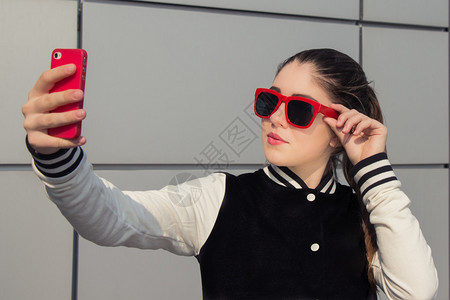 穿红色太阳眼镜的时髦少女用手机图片