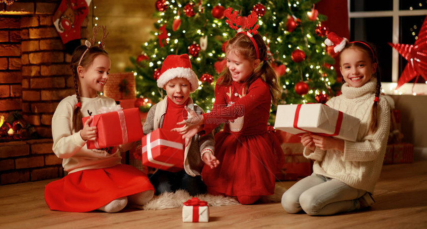 圣诞快乐圣诞树和壁炉附近的孩子们晚上回家带礼图片