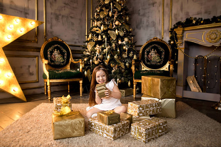 带着圣诞礼物盒坐在地板上的快乐图片