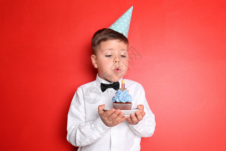 小男孩在生日蛋糕上吹蜡烛以彩图片