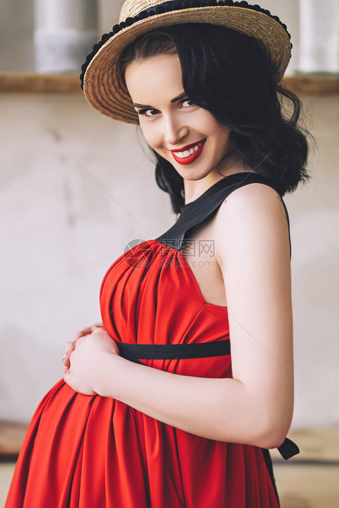 穿着长的红色sarafan和草帽的迷人时尚孕妇的时尚肖像图片