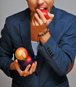 一个穿着蓝色西装外套的男人吃着红苹果图片