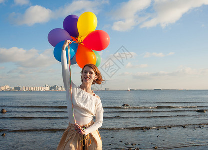 沙滩上拿着彩色气球的女孩图片