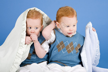 双胞胎男孩在明亮的蓝色背景下设置图片