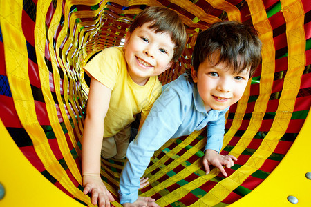 幸福的兄弟姐妹们在玩具隧道玩乐的同图片