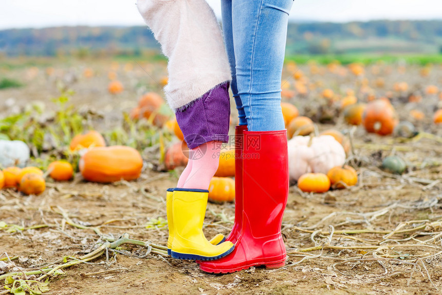 年轻女子和她的小女孩儿穿着雨靴的腿图片