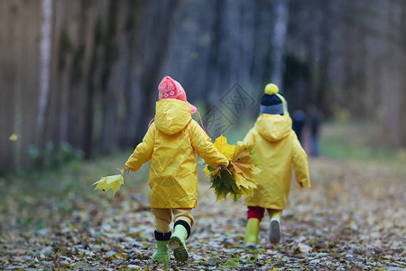 小孩子在落叶的秋天公园里散步图片