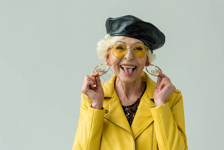 穿着黄色皮夹克耳环和黄色墨镜的时装年长妇女图片