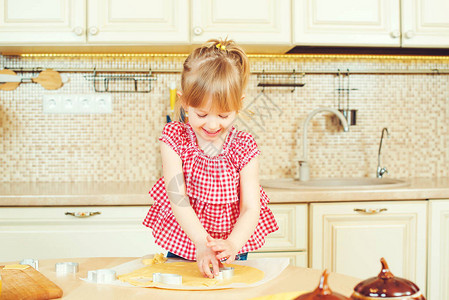 可爱的小女孩帮助她的母亲在厨房做饼图片